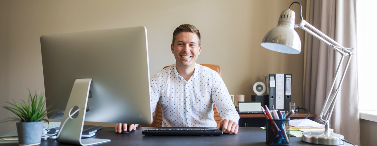 a-photo-of-an-accountant-sitting-at-a-desk-smiling--2VgLaf3SKG5JQkDnsnENA--poTK8ypQje4rnyG5gj59Q